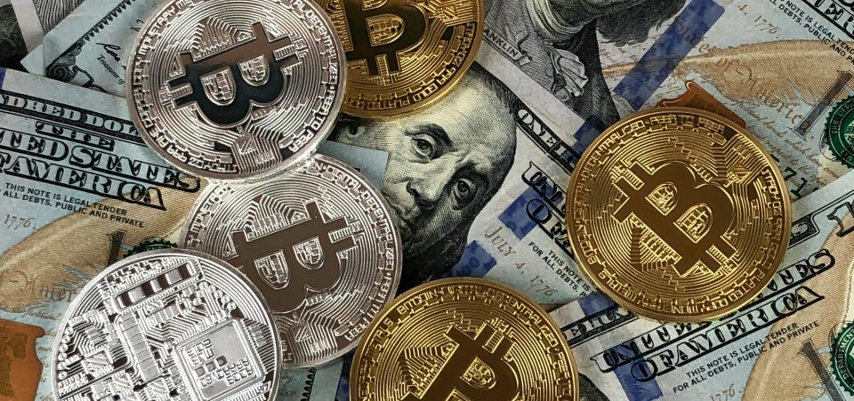 Bitcoin als Gold- und Silbermünze auf 100-Dollar-Noten