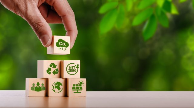 Person stapelt Nachhaltigkeitsziele als Würfel aufeinander