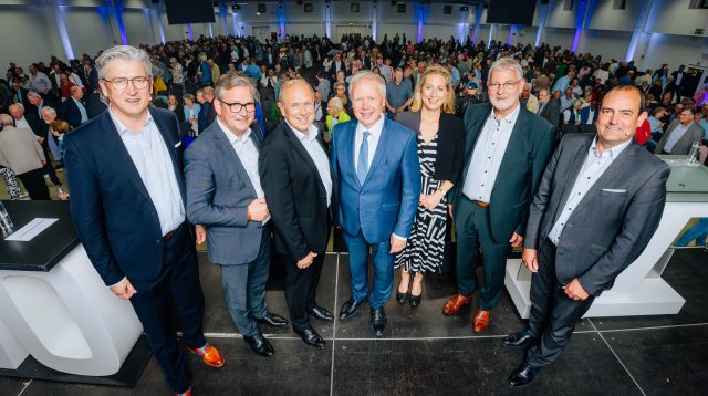 Der frühere WDR-Intendant Tom Buhrow kommt als Gast auf der Mitgliederversammlung der Verbundvolksbank OWL in die Mitte. Bankchef Ansgar Käter steht ganz links. Außerdem im Bild: Paderborns Bürgermeister Michael Dreier, Landrat Christoph Rüther, EU-Parlamentarierin Verena Mertens, Aufsichtsratschef Peter Gödde und Vorstand Thorsten Wolff. Foto: Besim Mazhiqi