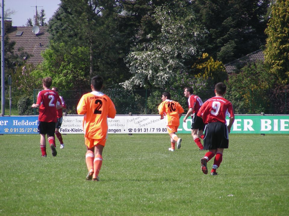 Fußballturnier eines lokalen Vereins: Jungen in roten und orangen Trikots spielen auf einem Fußballplatz Fußball.