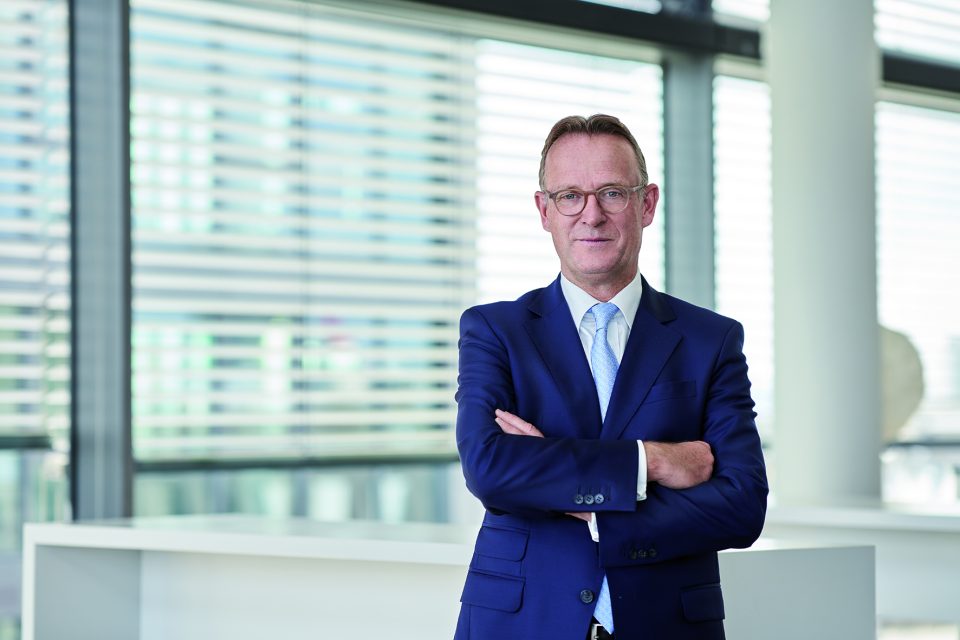 Ralf Lochmüller im blauen Anzug mit verschränkten Armen.